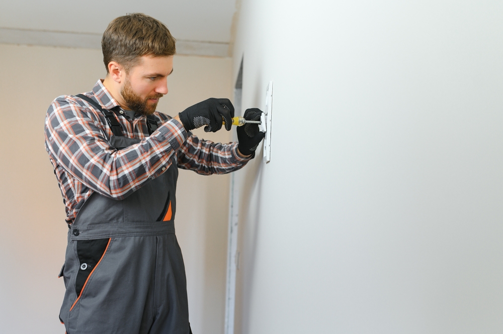 Electrician,With,Screwdriver,Repairing,Power,Socket,In,Room.